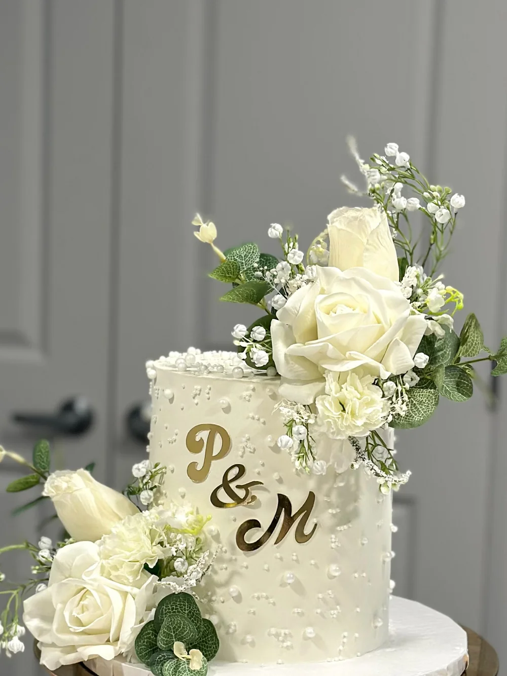 Pearl-detailed ivory cake with white roses and botanical accents